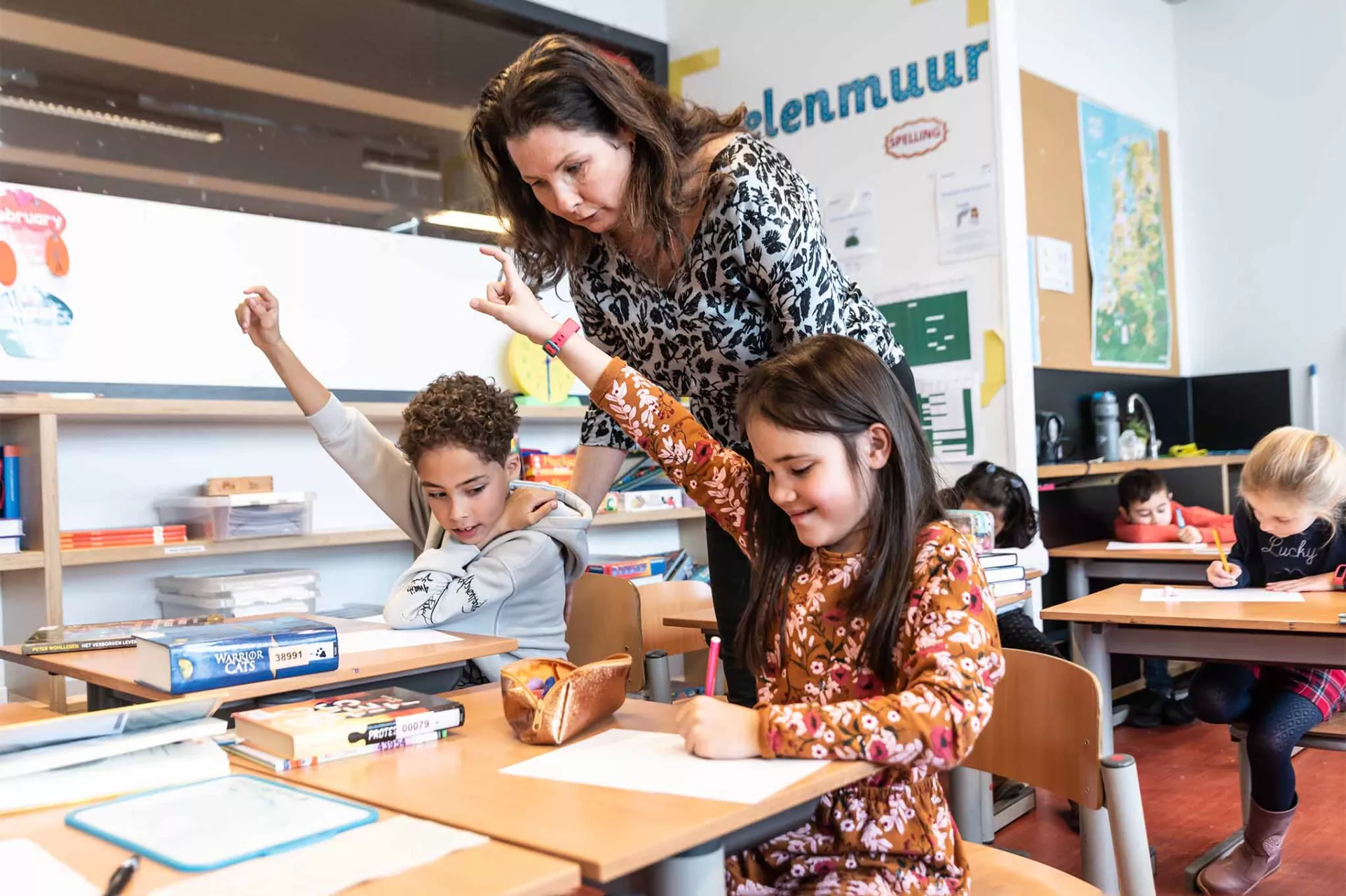 leerkracht helpt leerlingen tijdens schoolopdracht