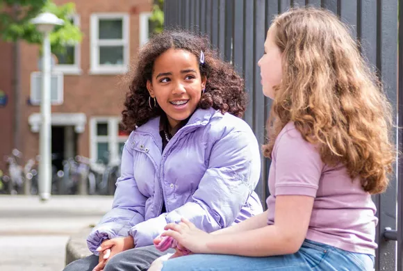 twee leerlingen praten met elkaar op het schoolplein