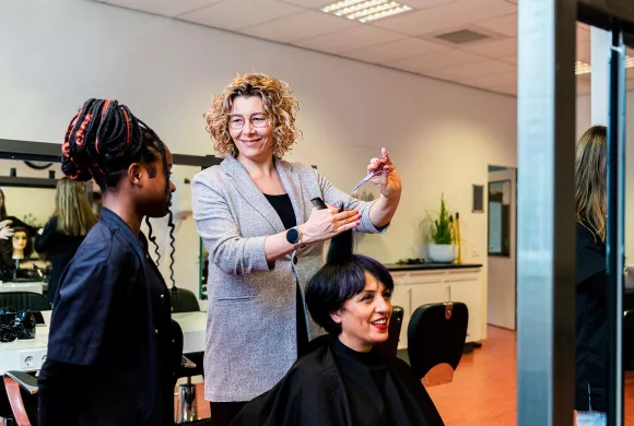 docent kappersopleiding Alfa college doet handeling voor bij student