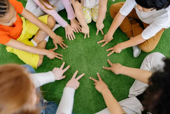 leerlingen vormen kring met hun handen op de grond