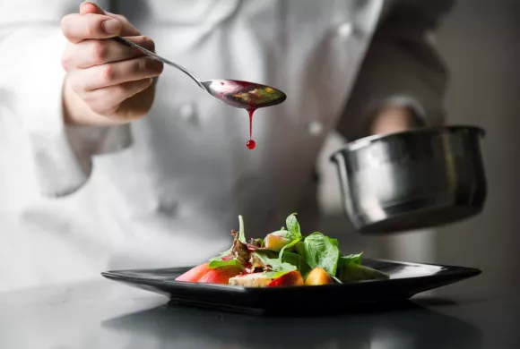 student van koksopleiding maakt bord op