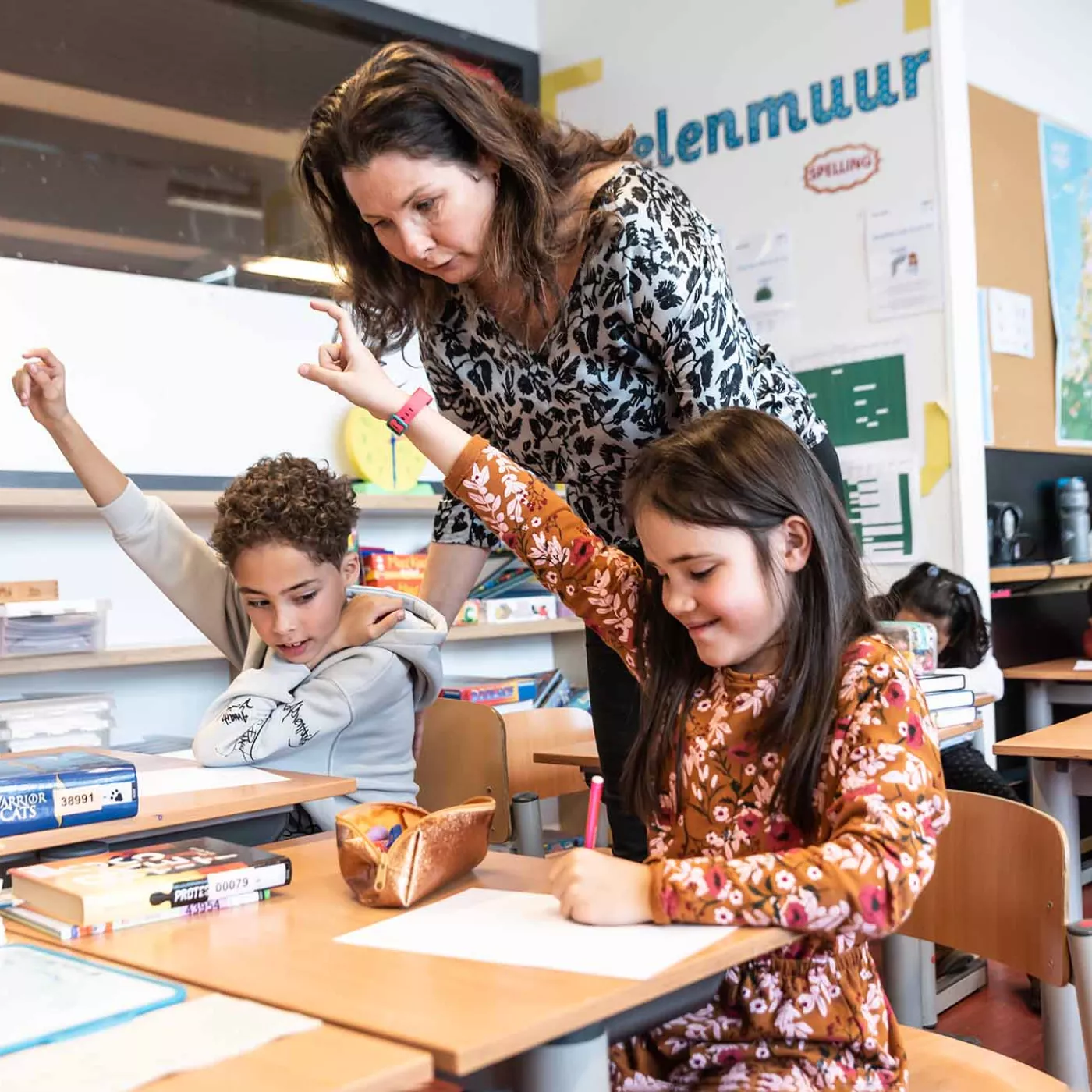 leerkracht helpt leerlingen tijdens schoolopdracht