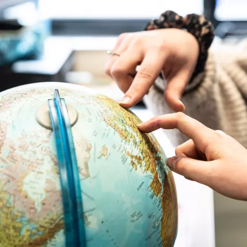 wijzende handen naar plaatsen op wereldbol