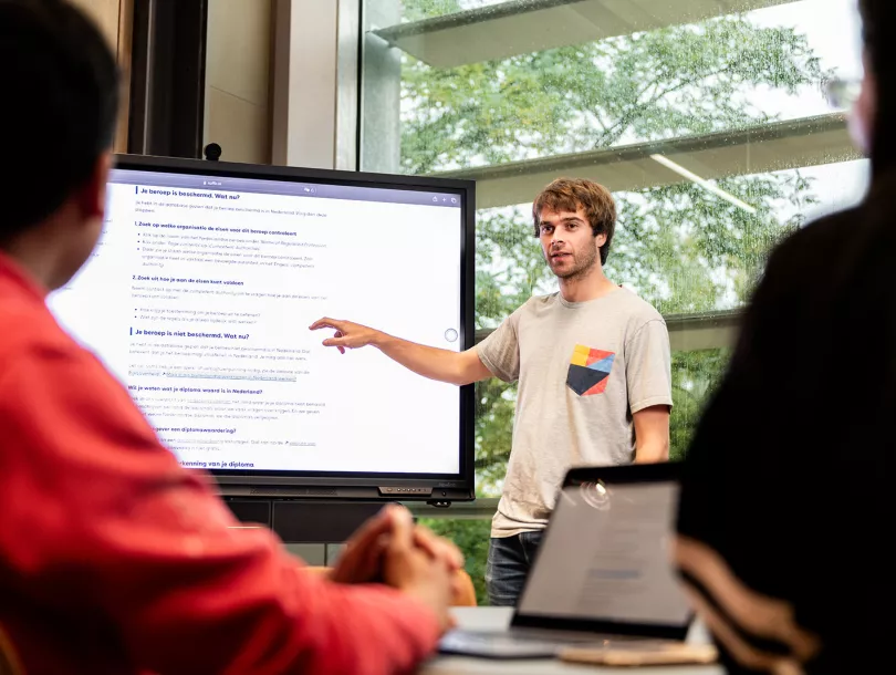 Persoon voor een digibord die iets uitlegt