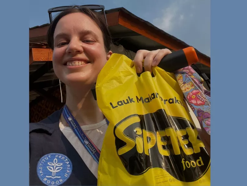 Rozemarijn de Wit, a Master's student from the University of Groningen, smiles while holding a bag of local Indonesian crackers during the H2O Summer Course in Indonesia.