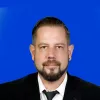 Profile Picture of Joerg Meijer wearing black suit with a tie in a blue back ground