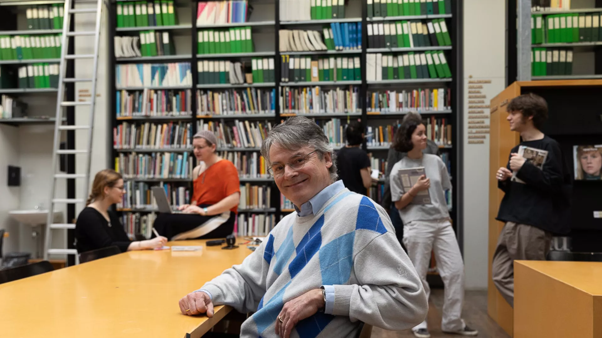 docent kijkt vriendelijk met studenten op de achtergrond, in een bibliotheek 